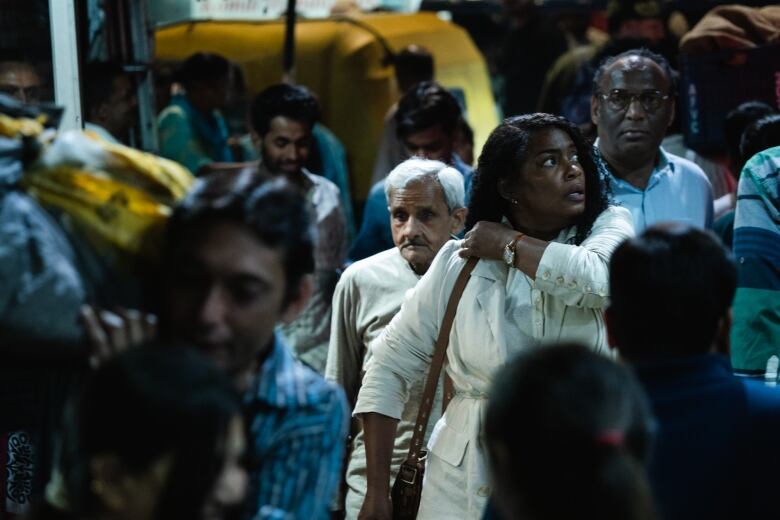 An African American woman in the middle of a crowded street in India. 