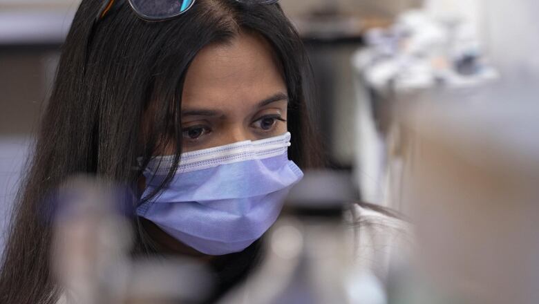 Female scientist wearing a lab coat and mask.