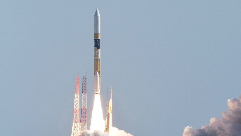 A pencil-shaped rocket is shown leaving a platform, with massive clouds of smoke trailing on the ground.