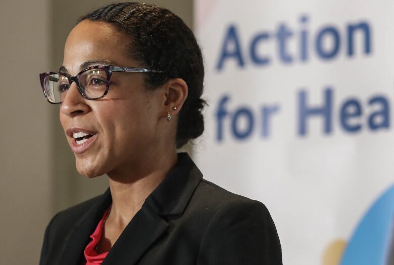 A woman with glasses stands at a podium.