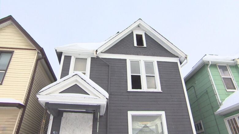 A vacant three-storey building with broken windows and boarded up doors.