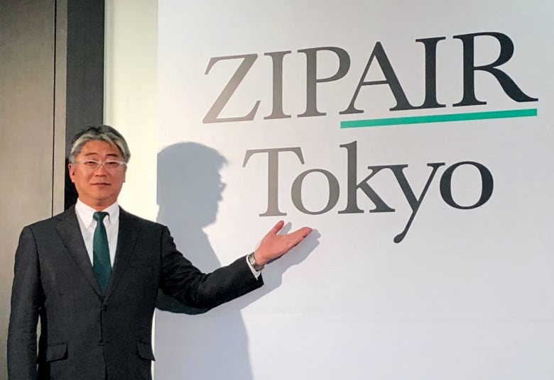 An East Asian man points to a logo reading 'Zipair Tokyo'.