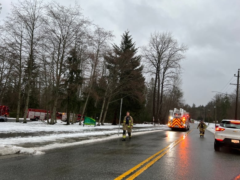 Firefighters walk along a snowy road.