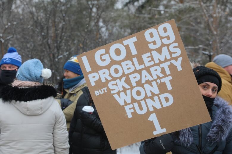 A woman holds a sign with the phrase 