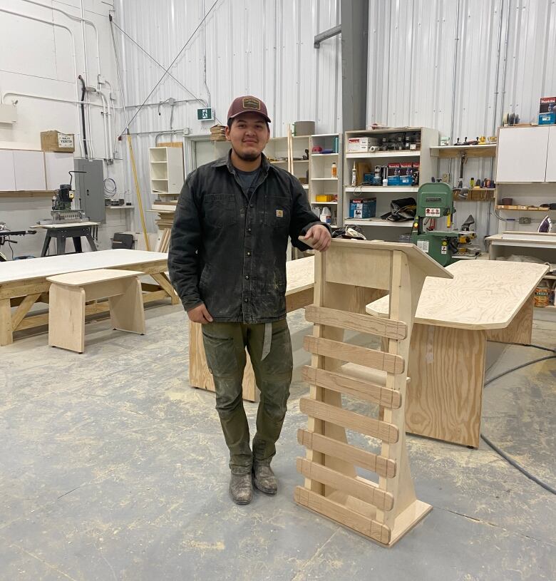 A young Inuk man stands in front of the items he has crafted from wood for the Nunavut devolution ceremony. 