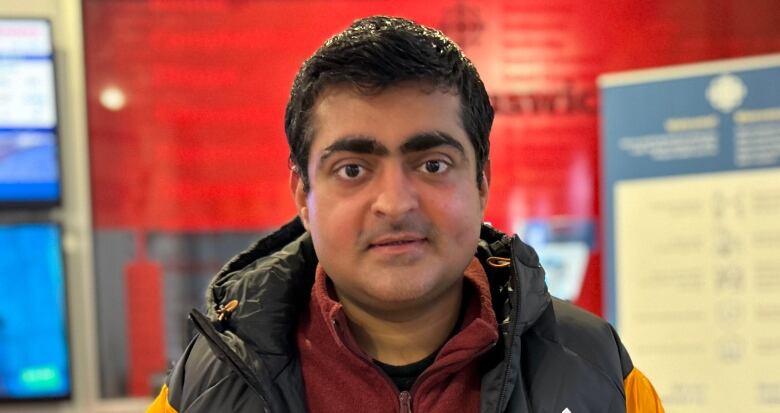 Man looking straight at the camera, standing in front of CBC signs.