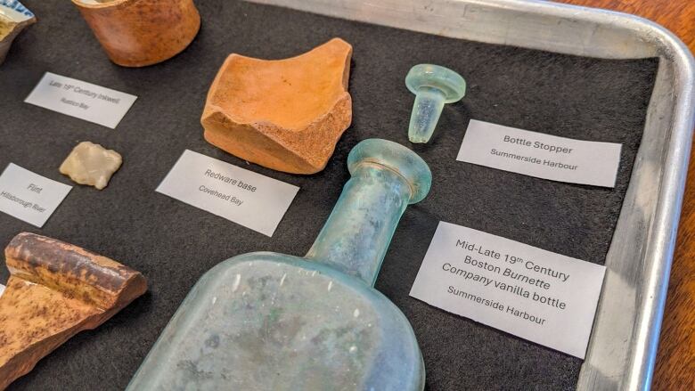 Old objects displayed on a silver tray with labels next to each one.