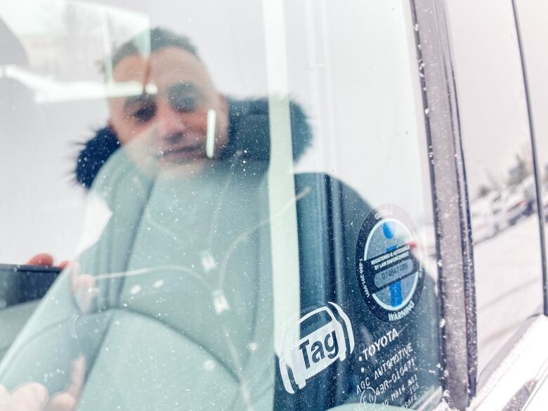 A 'Tag' logo etched on a vehicle window. Someone's also reflected in the window.