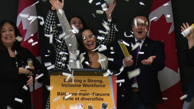 A woman and others at a podium in the midst of confetti