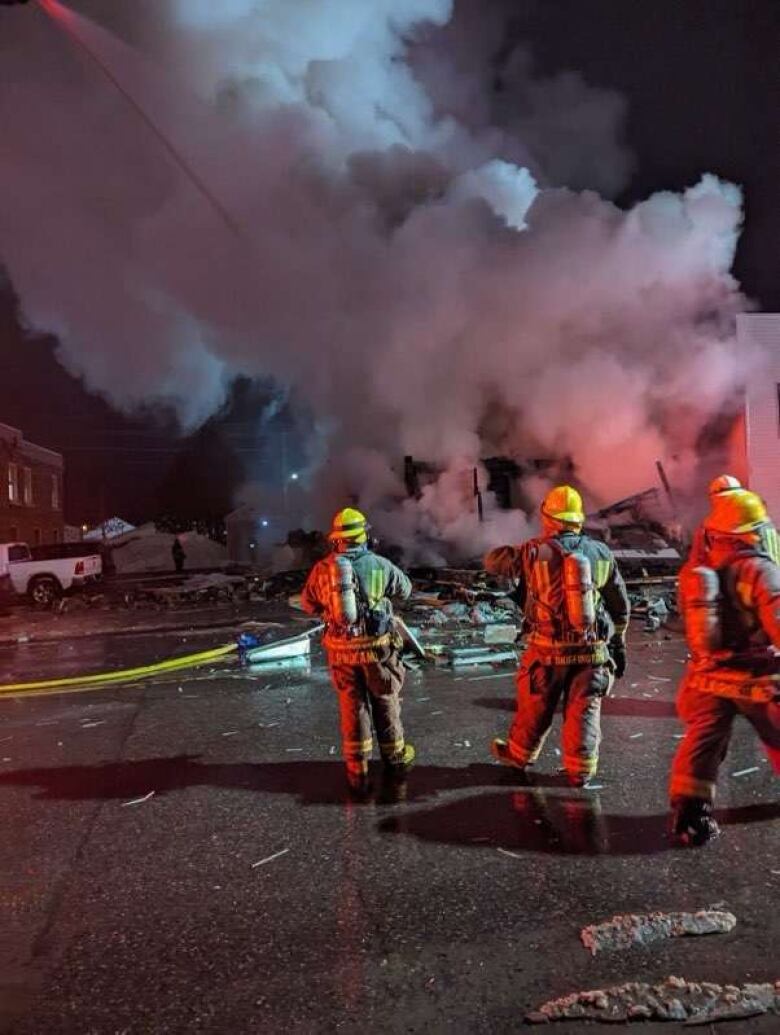 Three firefighters with smoke in the background.