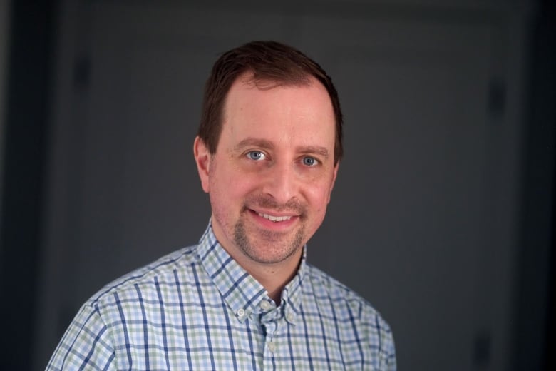 Portrait photo of an adult caucasian man wearing a red and green striped shirt.