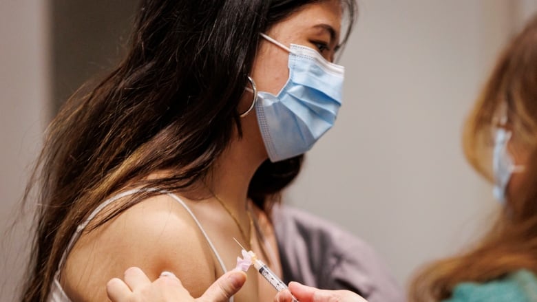 Teenage girl gets a vaccination from a Toronto Public Health nurse at a school immunization clinic.