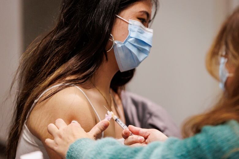 Teenage girl gets a vaccination from a Toronto Public Health nurse at a school immunization clinic.