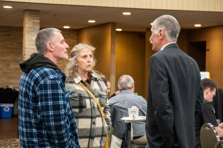 Three people speak with each other. 