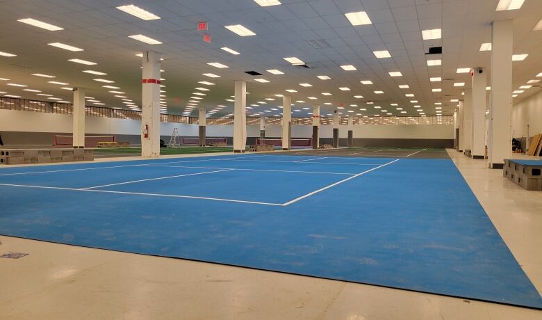 A large empty gym space with blue mats is pictured.