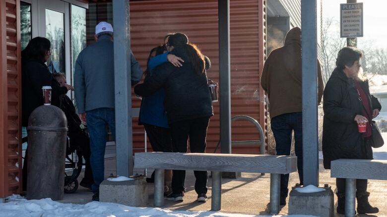 The photo shows the backs of a number of people, including two people who are hugging.