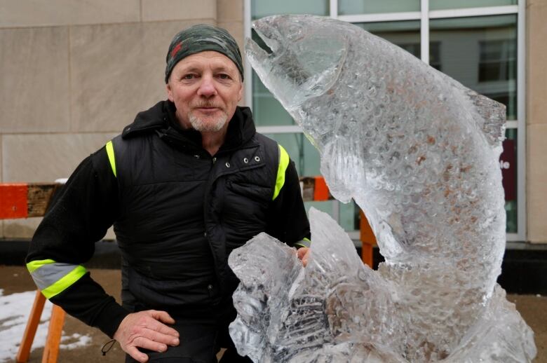 A man stands behind an impressive ice sculpture of a leaping salmon.