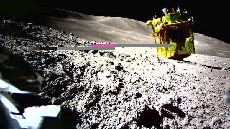 A cubic gold lander sits on the rocky surface of the moon