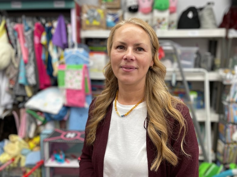 A blonde woman standing in a small store.