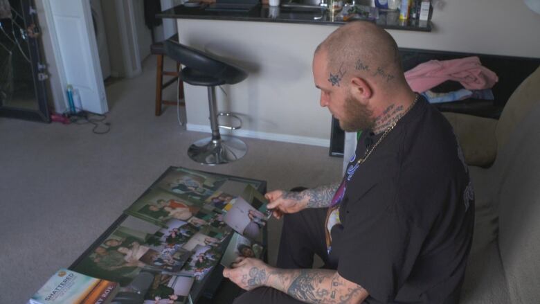 A man sits on a couch and looks at photos. 