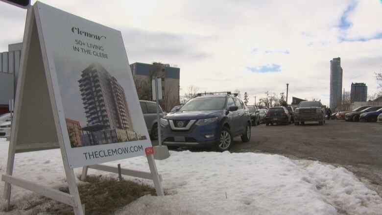 A flipboard in a parking lot advertises a high-rise tower