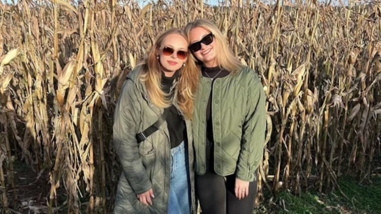 Two young women with arms around each other in a sunny field