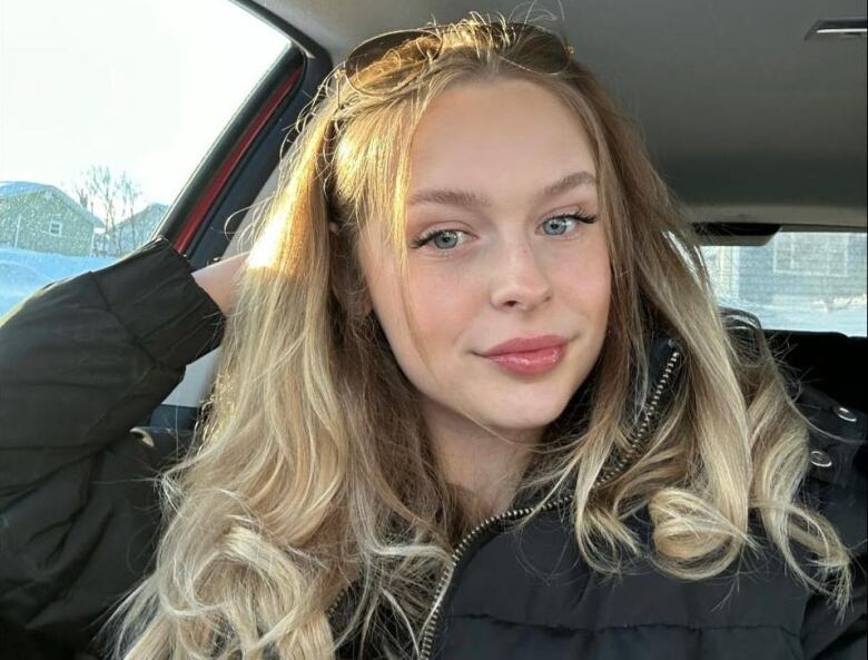 A selfie of a blond woman smiling in a car