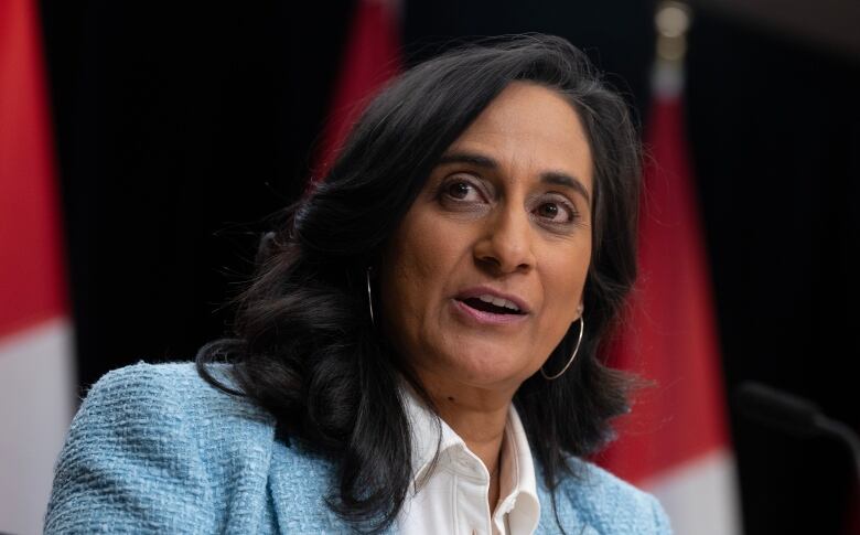 A woman in a blue blazer speaks in a press conference room.