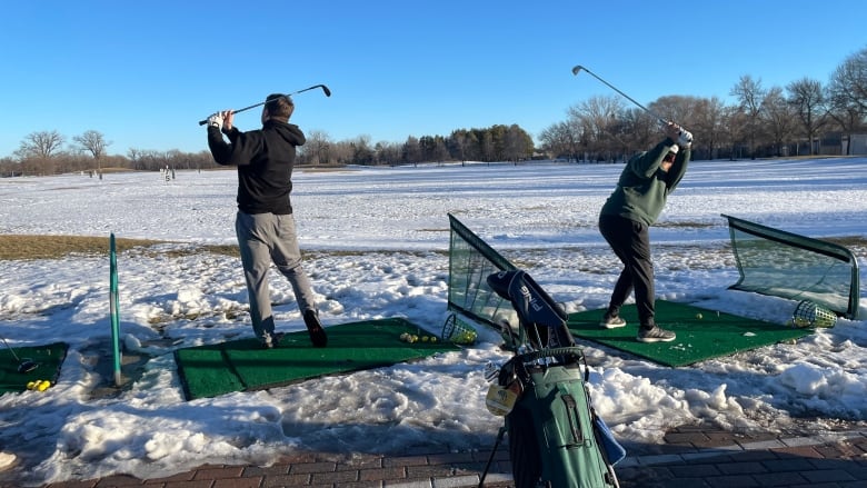 People swinging golf clubs in a snowy field.