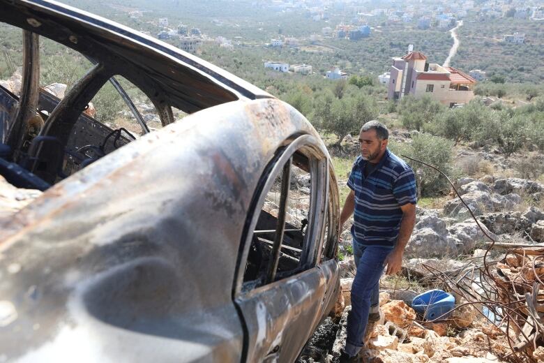 A Palestinian checks a car burned in an Israeli settlers raid near Salfit in the Israeli-occupied West Bank December 3, 2023. 