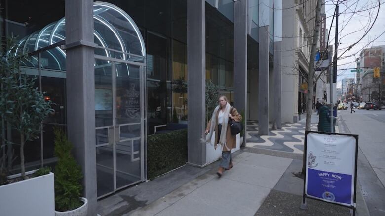 A restaurant patio with a woman walking in front.