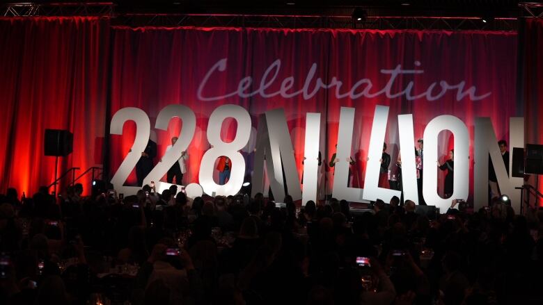 People holding big letters that spell '22.8 million' in a stage.