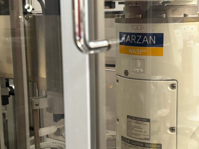 Photo of a robot taken from a glass window with label 'TARZAN' attached to it.