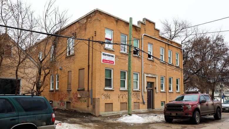 Cars are parked outside a brick apartment building.