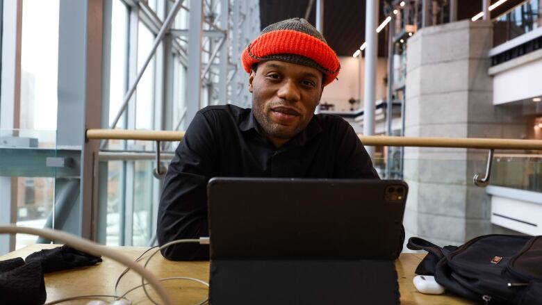 A man sitting behind a tablet device at a library.