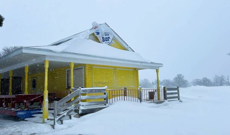 Yellow building with ice cream sign covered in snow.