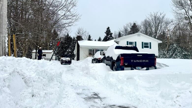 A driveway with snow encasing two vehicles.