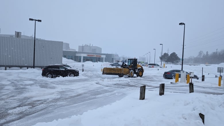 Tractor pushes snow in hospital parking lot