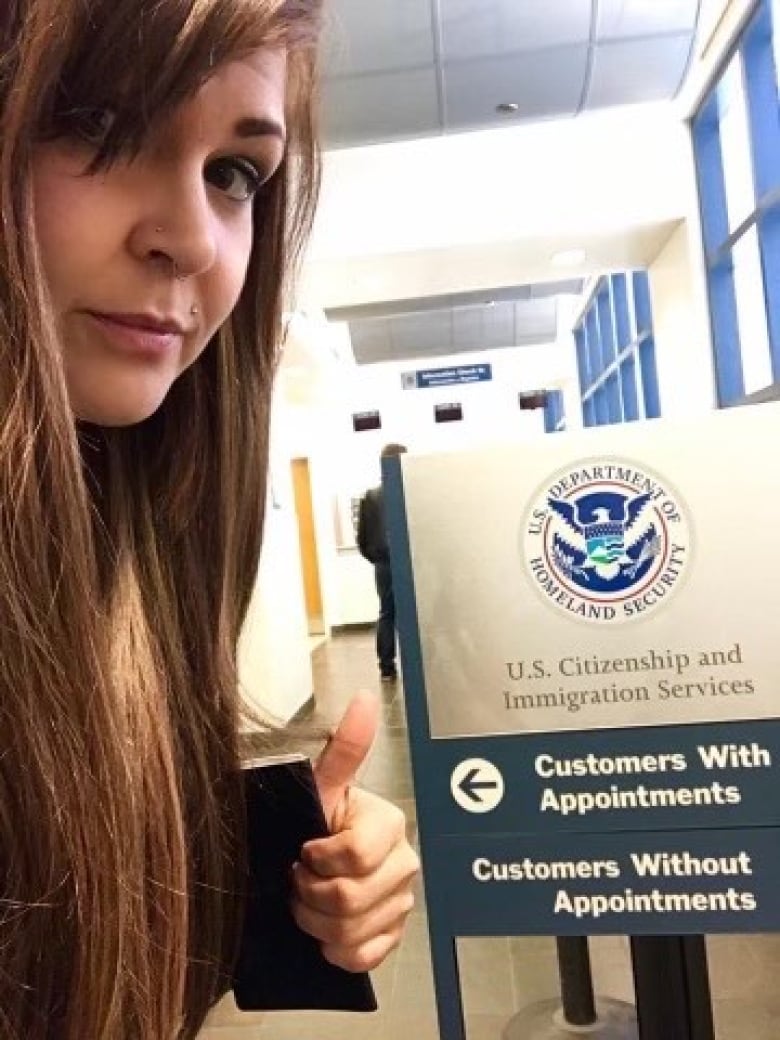 Kale Bonham giving a thumbs up in front of a U.S. Immigration office sign.