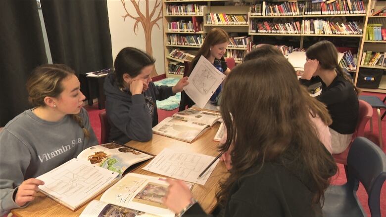 Students sit around a table in the library at Ecole Pierre Chaisson.