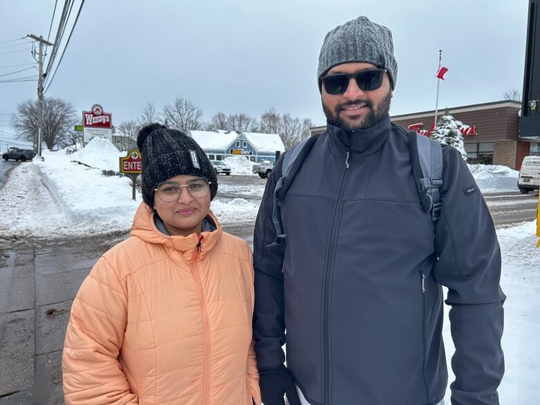 Man and woman standing in snowy parking lot.