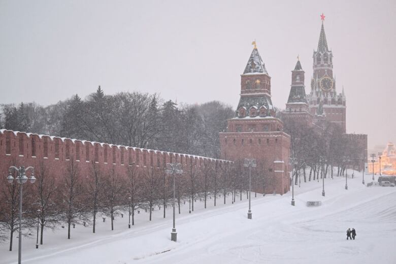 People walk on the edge of Red Square outside the Kremlin during a heavy snowfall in Moscow on February 7, 2024.