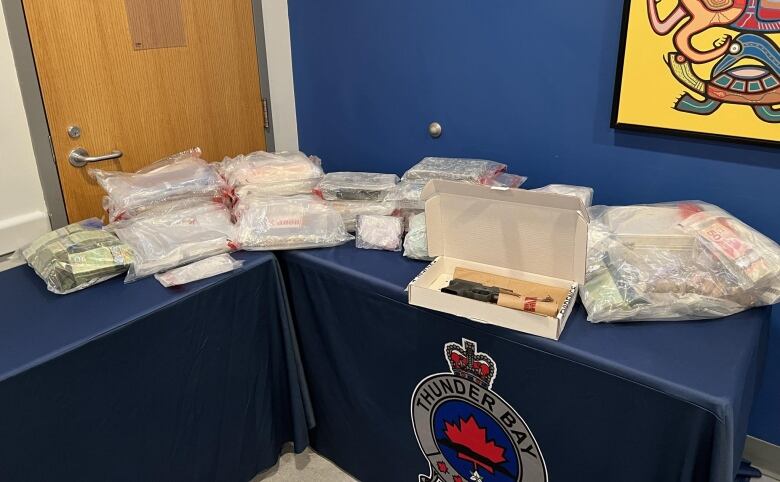 A table containing plastic bags of seized items, including cash and a handgun.