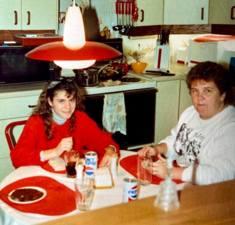 A retro photo of a girl and a woman sharing a meal together. 