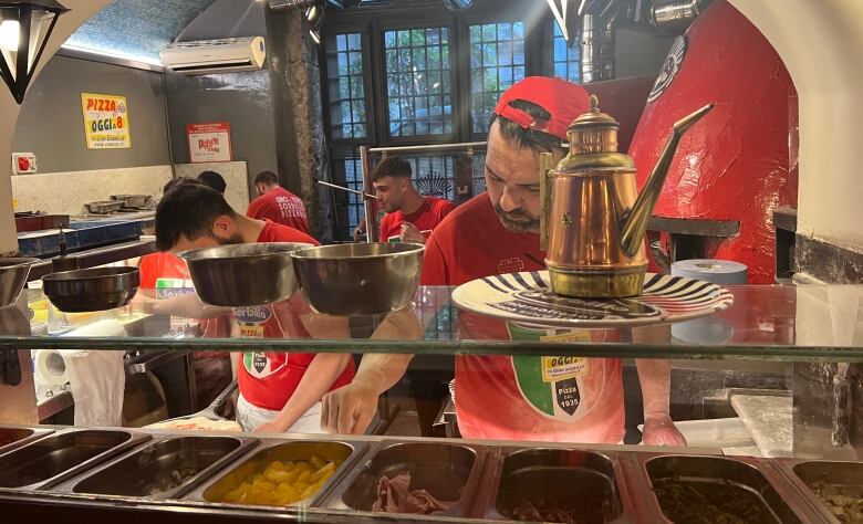 Workers make pizzas in an Italian pizzeria. 