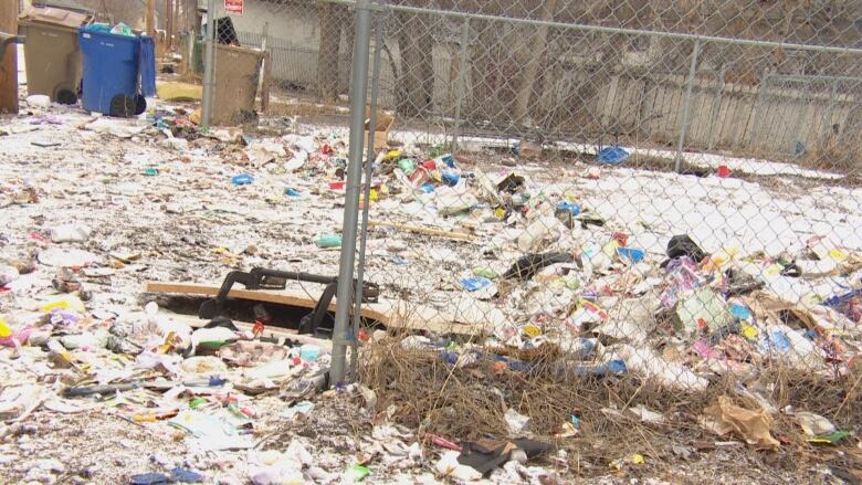 Garbage lies on the ground in an alley.