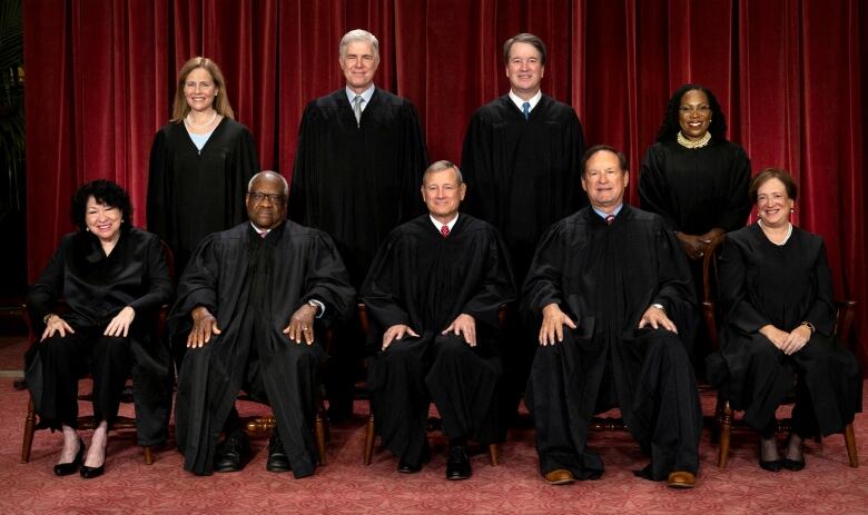 Nine people, comprising five men and four women, are shown posing for a group photo in judicial robes.