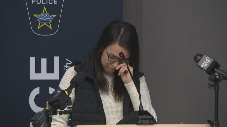 A young woman holds back tears at a police podium