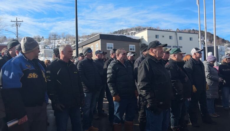 A group of men in winter jackets standing in a parking lot