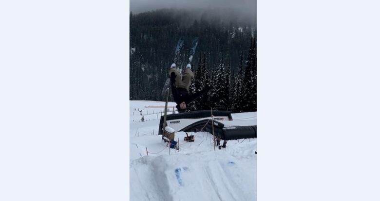 A skier mid-air flipping over a jump